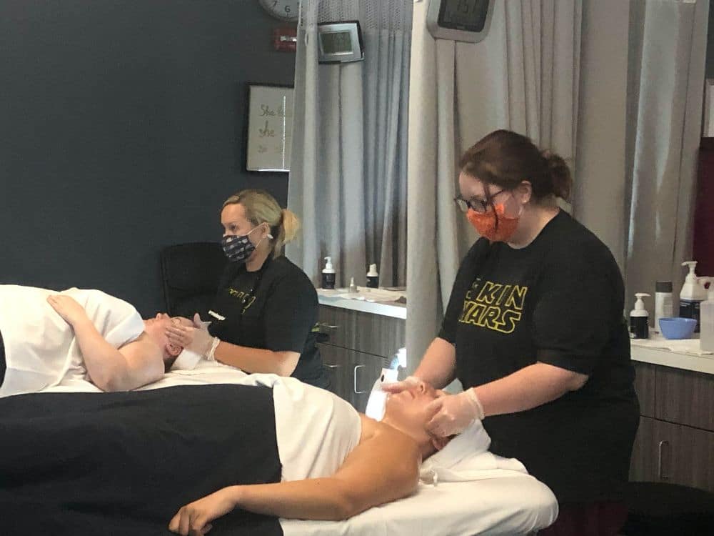This is an image of esthetics students performing facials on clients in the clinic. Students are wearing masks for due to COVID.