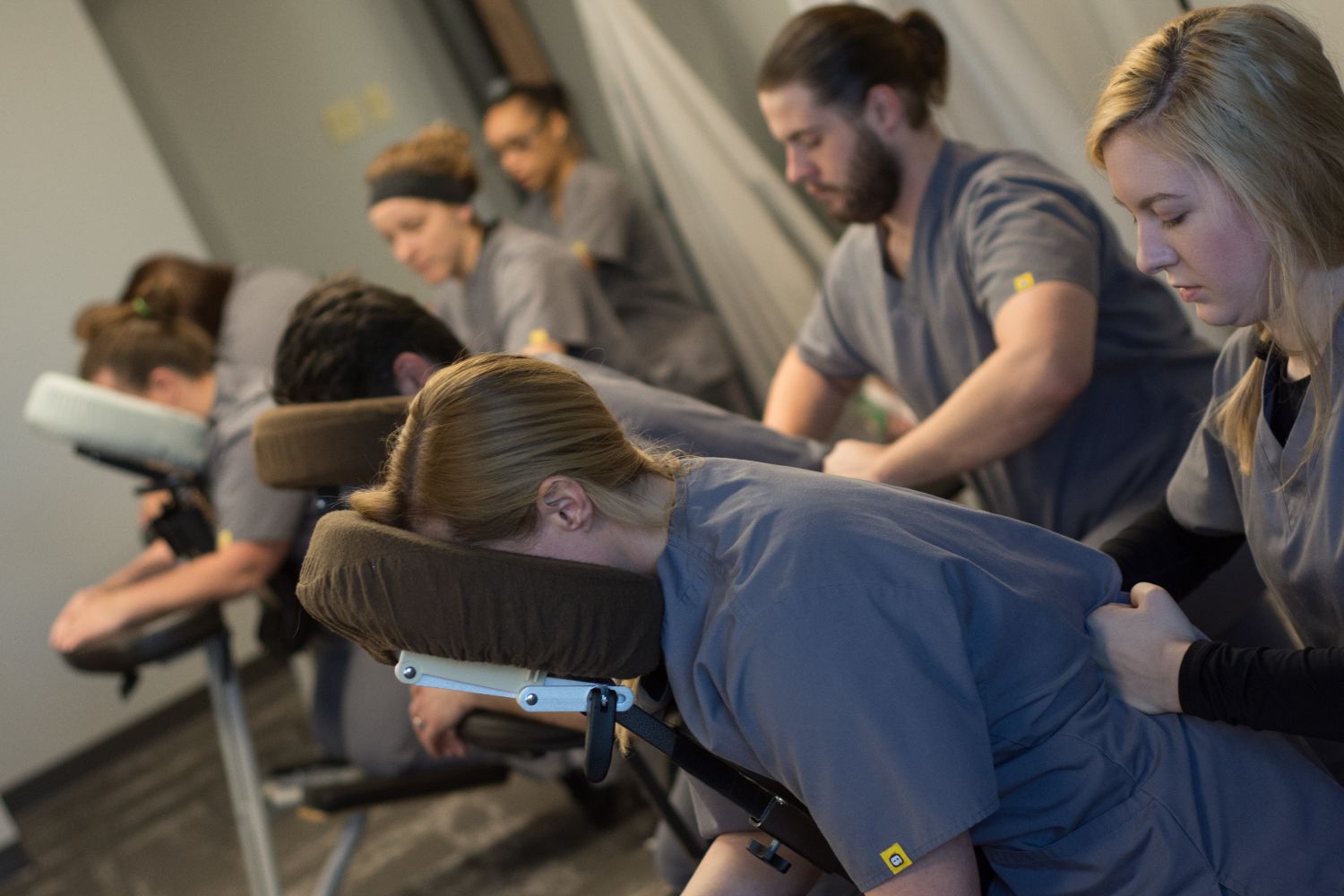 This is an image of massage students in massage chairs receiving massages from other students to practice their skills.