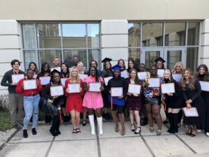 23 individuals standing with diplomas